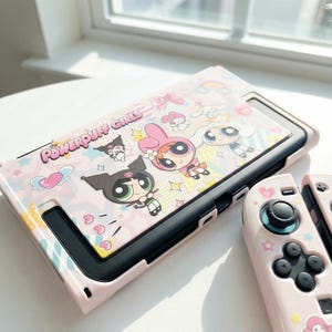Puede incluir: Una funda rosa para Nintendo Switch con personajes de Las Supernenas y el texto "Powerpuff Girls". La funda tiene un mando rosa a juego. El diseño incluye personajes de dibujos animados, corazones y estrellas.