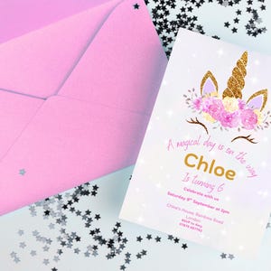 May include: A pink envelope and a birthday invitation with a unicorn design. The invitation has gold text that reads "Chloe Is Turning 6" and includes event details. The invitation is decorated with floral and glitter accents.