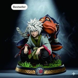 Puede incluir: Figura detallada de un personaje con pelo blanco puntiagudo, vistiendo un atuendo verde y rojo, y una rana. La figura está sobre una base con hierba y un borde dorado y negro. La palabra "Bestseller" está en la esquina superior izquierda.