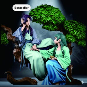 Puede incluir: Figura detallada de dos figuras de estilo anime, una con cabello morado y la otra con cabello verde, vestidas con túnicas fluidas. Están sentadas en una rama de árbol con un exuberante dosel verde. La palabra "Bestseller" está en un óvalo blanco.