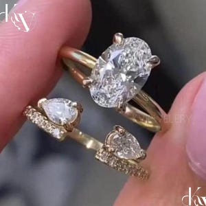 May include: A gold ring set consisting of an oval-cut center stone ring and a matching open-style band featuring two pear-cut stones and small pavé-set diamonds along the shank. The jewelry pieces are crafted from polished yellow gold metal.