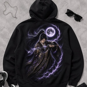 Peut inclure: Sweat à capuche noir avec un motif détaillé d'un samouraï tenant un katana sous une pleine lune, entouré d'éclairs violets. Le motif est au dos. Des lunettes de soleil, une chaîne argentée et des baskets sont également visibles.