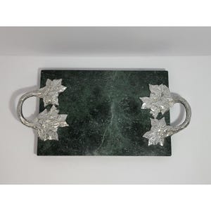 May include: A rectangular dark green marble serving tray featuring two silver-toned metal handles shaped like clusters of leaves and branches attached to the left and right sides of the stone base.