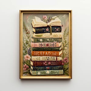 May include: A framed print featuring a stack of vintage books with floral embellishments. The books are in various colors, with the word "READ" visible on one. The artwork is surrounded by a gold frame and floral accents.