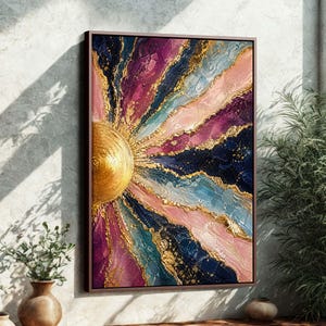 May include: Abstract art print featuring a golden sunburst design with textured layers in shades of pink, purple, blue, and navy. Gold accents highlight the radiating lines, framed in a dark brown border. The artwork is displayed on a wall with a neutral background.