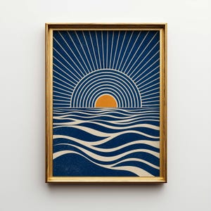 May include: Framed art print featuring a stylized sunset over ocean waves. The artwork uses a palette of navy blue, cream, and orange. The sun is depicted as a half-circle with radiating lines, and the waves are flowing. The gold frame adds a touch of elegance.