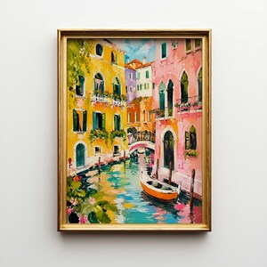 May include: A framed painting depicts a colorful canal scene. Buildings in shades of yellow, pink, and orange line the waterway. A small orange boat floats on the water. The painting is in a gold frame.