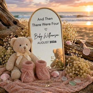 Puede incluir: Un espejo arqueado con el texto And Then There Were Four, Baby Williamson y AUGUST 2026, acompañado de un oso de peluche beige con lazo crema, patucos de punto rosa, una pulsera dorada con la letra A y pequeñas conchas marinas.