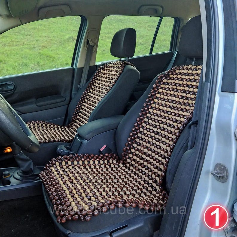 May include: Two car seat covers constructed from small, polished wooden beads arranged in a grid pattern. The beads alternate between dark brown and light tan colors, creating a striped design that covers the backrest and seat of the vehicle chairs.