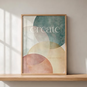 Könnte beinhalten: Ein rechteckiges Wandbild in einem hellen Holzrahmen mit überlappenden, halbtransparenten Kreisen in gedeckten Blaugrün-, Gelb- und Terrakottatönen. Das Wort "create" ist in Weiß gedruckt, darunter steht der Text "TURN IDEAS INTO FORM".