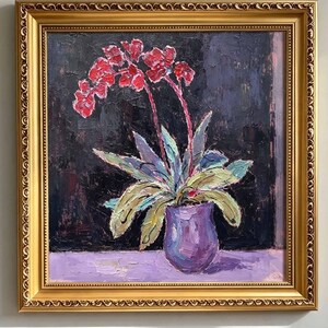 Puede incluir: Una pintura al óleo en un marco dorado ornamentado que representa una orquídea en maceta con flores rojas vibrantes y hojas verdes en un jarrón morado. El fondo es una superficie negra texturizada y la base es un plano morado claro. Texto: LUCKYARTSGALLERY.