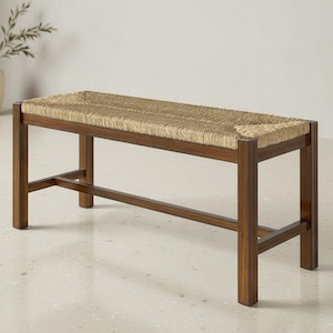 May include: A rectangular bench featuring a dark brown wooden frame with four straight legs and horizontal support bars. The seat is constructed from woven light tan natural fiber, creating a textured surface across the top of the bench.