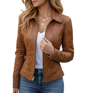 Könnte beinhalten: Braune Lederjacke mit Kragen und Reißverschluss vorne. Die Jacke hat eine kleine Tasche mit Schnalle auf der linken Seite. Das Model trägt ein weißes Oberteil und blaue Jeans.