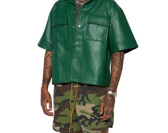 May include: A short-sleeved forest green button-down shirt made of a smooth material, featuring a classic collar and two chest pockets with flaps. The shirt is paired with camouflage print shorts that have a drawstring waist with yellow cords.