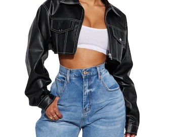 May include: A black cropped jacket with long sleeves, a pointed collar, and a front zipper closure. The jacket features two chest pockets with flaps and prominent white contrast stitching along the seams, pockets, and collar edges.