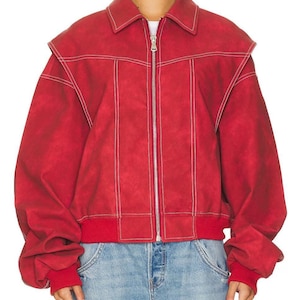 May include: Red bomber jacket with white stitching. The jacket has a collar, a zip, and red ribbed cuffs and hem. The sleeves are voluminous, and it's worn with blue jeans. The jacket's measurements are in centimetres.