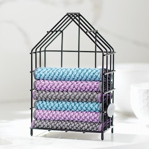 May include: A black metal house-shaped storage basket filled with rolled, textured towels. The towels are in shades of blue, purple, and gray. A small white tag is attached to the side of the basket. The towels are neatly stacked inside the black metal frame.