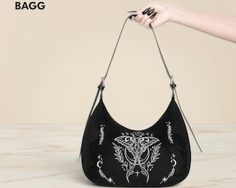 May include: Black crescent-shaped handbag with a white moth and botanical design. The bag has a long, thin strap and silver-toned hardware. The text "NOVA BAGG" is in the upper left corner.