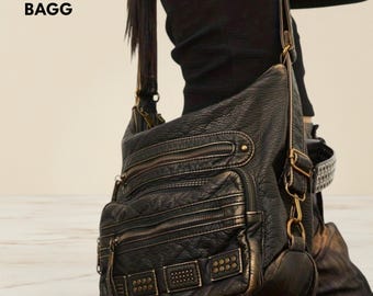 May include: Black leather shoulder bag with multiple zippered compartments and decorative metal studs. The bag has a long adjustable strap and the text "NOVA BAGG" is visible in the upper left corner.