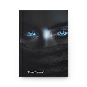 May include: A black journal with the text "Eye of Creation." The cover features a close-up of bright blue eyes peering from behind a dark fabric. The image has a dramatic, artistic quality.