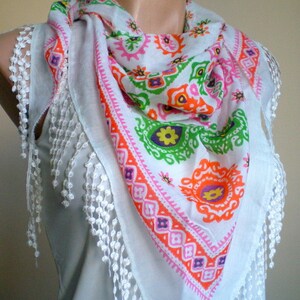 K&ouml;nnte beinhalten: Wei&szlig;er Baumwollschal mit einem bunten geometrischen Muster und wei&szlig;en Fransen. Das Muster ist in den Farben Pink, Orange, Gr&uuml;n und Lila gehalten.