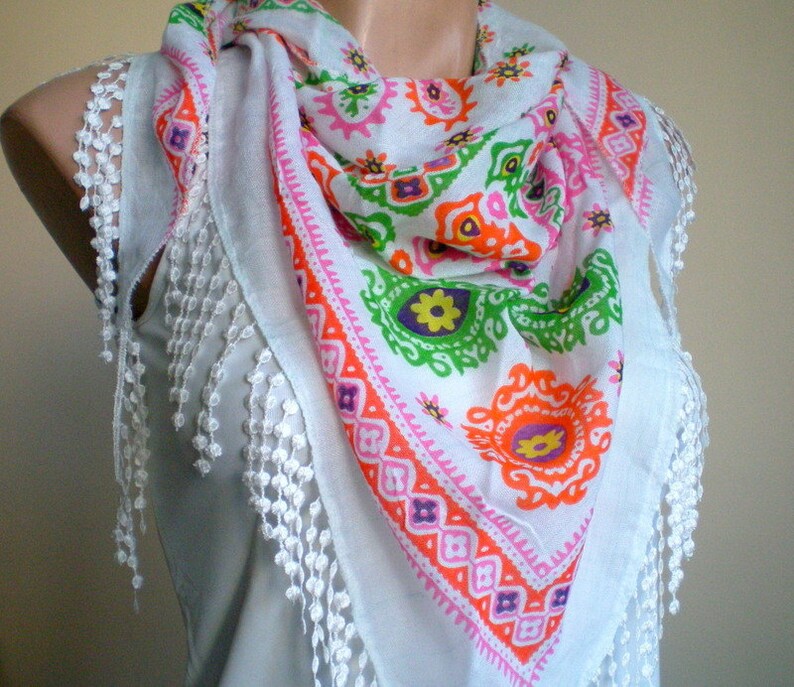 K&ouml;nnte beinhalten: Wei&szlig;er Baumwollschal mit einem bunten geometrischen Muster und wei&szlig;en Fransen. Das Muster ist in den Farben Pink, Orange, Gr&uuml;n und Lila gehalten.