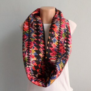 Puede incluir: Una bufanda infinita negra con un estampado floral colorido. La bufanda est&aacute; hecha de una tela suave y c&oacute;moda y es perfecta para agregar un toque de color a cualquier atuendo.