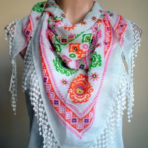 K&ouml;nnte beinhalten: Wei&szlig;er Baumwollschal mit einem bunten geometrischen Muster und wei&szlig;en Fransenbesatz. Das Muster ist in den Farben Pink, Orange, Gr&uuml;n und Gelb gehalten.