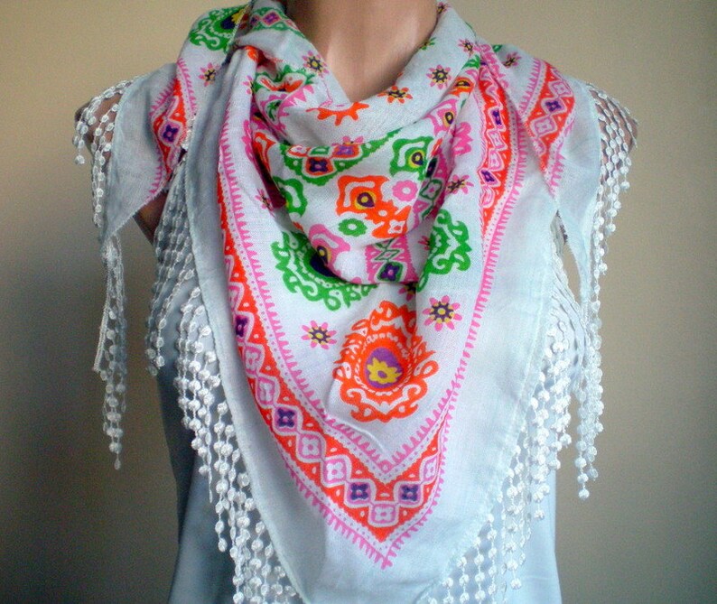 K&ouml;nnte beinhalten: Wei&szlig;er Baumwollschal mit einem bunten geometrischen Muster und wei&szlig;en Fransenbesatz. Das Muster ist in den Farben Pink, Orange, Gr&uuml;n und Gelb gehalten.