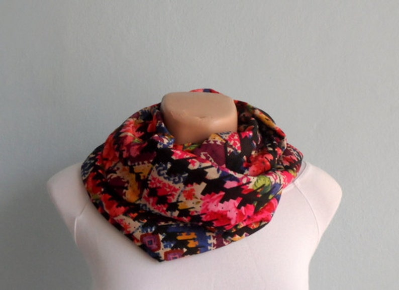 Puede incluir: Una bufanda infinita colorida con un patr&oacute;n geom&eacute;trico negro, rosa, amarillo y azul.