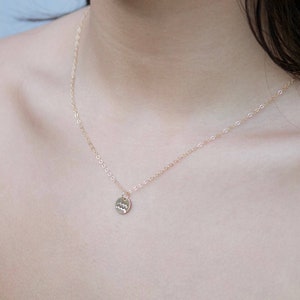 May include: A gold chain necklace with a small, round pendant featuring the astrological symbol for Aquarius.