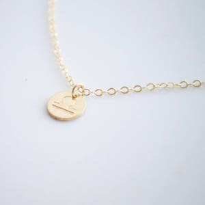 May include: Gold necklace with a Libra zodiac sign pendant. The pendant is a small, round disc with the Libra symbol engraved on it.