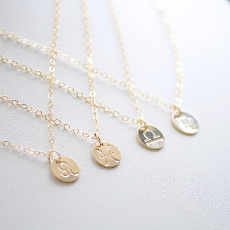 May include: Four gold necklaces with zodiac signs as pendants. The signs are Pisces, Leo, Libra, and Virgo.