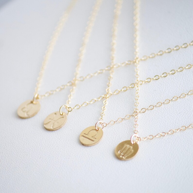 May include: Five gold necklaces with zodiac symbols as pendants. The symbols are Pisces, Aquarius, Libra, Virgo, and Sagittarius.