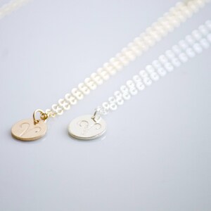 May include: Two delicate necklaces with a silver and gold pendant featuring the zodiac symbol for Aries. The necklaces are made of a fine chain.