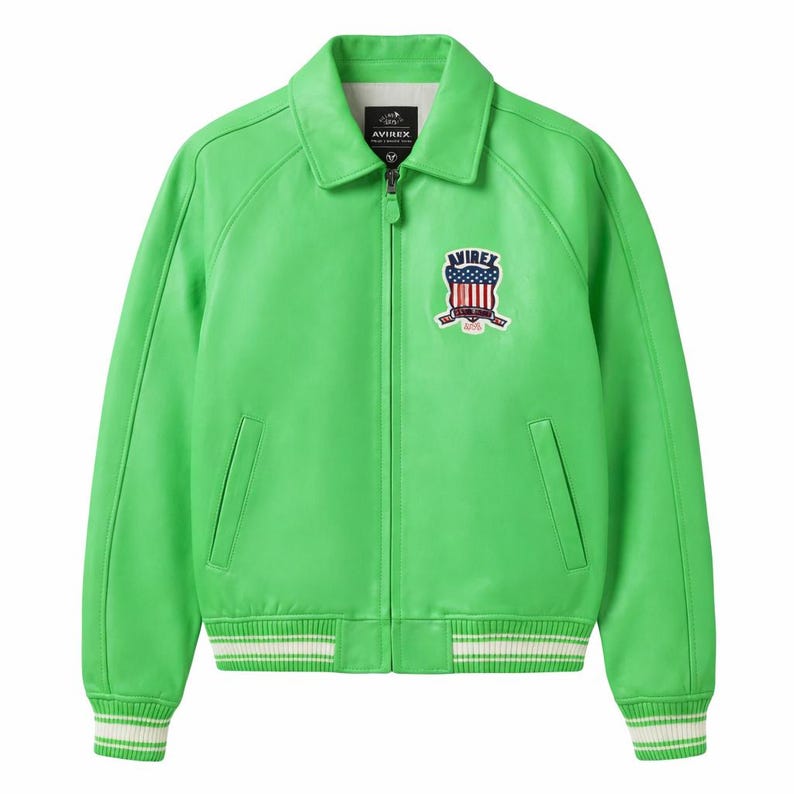 May include: Bright green leather jacket with a collared neckline and a zip-up front. The jacket features a patch with a red, white, and blue design on the chest and white and green striped cuffs and hem. The brand name "AVIREX" is visible on the patch.