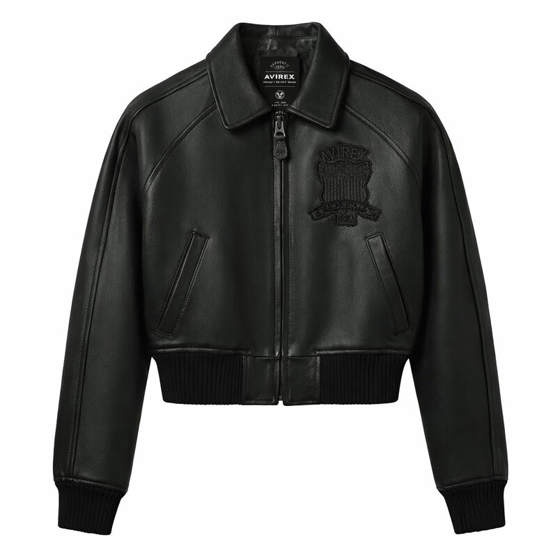 Puede incluir: Chaqueta bomber de cuero negro con cuello, cierre de cremallera y pu&ntilde;os y dobladillo acanalados. Cuenta con un parche con el logo en el pecho y el nombre de la marca "AVIREX" en el cuello.