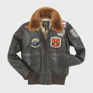 Puede incluir: Chaqueta bomber de cuero marrón con cuello de borrego. La chaqueta presenta varios parches, dos bolsillos delanteros y cierre de cremallera. Los puños y la cintura son de un marrón más oscuro. La chaqueta tiene un estampado de mapa en el interior.