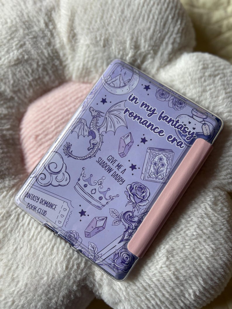 May include: A lavender-colored tablet case with a pink side. The case features a fantasy-themed design with a dragon, stars, crystals, roses, and the text "in my fantasy romance era" and "Give me a Shadow Daddy".