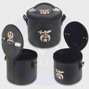 May include: A black cylindrical carrying case with a top handle and a zipper closure. The exterior features a decorative emblem with a crescent moon, a star, and a scimitar, embellished with small white, red, and gold-toned stones on the lid and side.