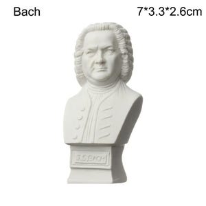 May include: A white bust of Johann Sebastian Bach, with the name "Bach" above the bust. The bust is 7 inches tall, 3.3 inches wide, and 2.6 inches deep. The bust has a detailed face and hair, and the base reads "J.S. BACH."