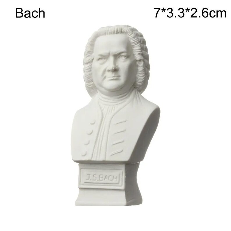 May include: A white bust of Johann Sebastian Bach, with the name "Bach" above the bust. The bust is 7 inches tall, 3.3 inches wide, and 2.6 inches deep. The bust has a detailed face and hair, and the base reads "J.S. BACH."