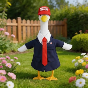 May include: A white goose figurine wearing a red baseball cap with the text MAKE AMERICA HONK AGAIN, a navy blue suit jacket, a white collared shirt, a red necktie, and a small American flag pin on the lapel, standing on orange webbed feet.