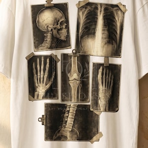 May include: A white short-sleeve t-shirt featuring a graphic print of multiple sepia-toned medical X-ray images, including a skull, rib cage, hand, knee, foot, and spine, attached with tape and clips. The text Pulse Oasis Studio is printed.