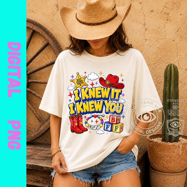 May include: A cream-colored t-shirt featuring a graphic print with the text "I KNEW IT I KNEW YOU" in blue and yellow. The design includes a yellow sheriff badge, a red cowboy hat, red cowboy boots, a beaded bracelet, and colorful alphabet blocks.