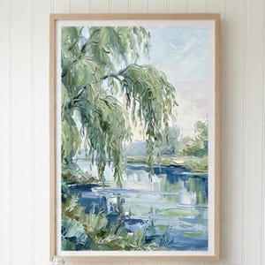 May include: A wall-mounted light wood folding desk featuring the text JunglefeverDesigns. Above the desk hangs a framed landscape painting of a willow tree by a river. On the desk sits a glass jar filled with wooden clothespins and a spray bottle.