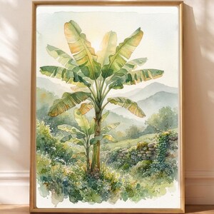 Könnte beinhalten: Ein vertikales, rechteckiges Wandbild in einem hellen Holzrahmen mit einem Aquarell eines Bananenbaums in einer üppigen Landschaft. Die Szene zeigt grünes Blattwerk, eine Steinmauer und ferne Berge unter einem hellen Himmel.