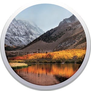 Può includere: Immagine circolare di un paesaggio montano con un lago. Le montagne sono marroni e innevate, con un lago che riflette i colori autunnali degli alberi. Gli alberi sono gialli e arancioni e il cielo è nuvoloso.