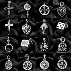 Può includere: Una collezione di ciondoli e charm argentati, con croci, gigli e altri disegni decorativi. I ciondoli sono esposti su uno sfondo scuro e strutturato, che mette in risalto i loro dettagli intricati.