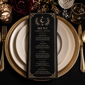 May include: A black menu card with gold decorative borders and text, featuring the names "Ophelia & Vincent" and a detailed menu. The menu includes starters, salads, entrees, and desserts. The card is set on a table with gold-rimmed plates and silverware.